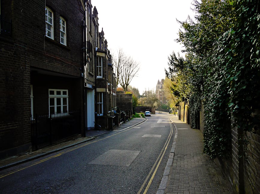 A row of traditional terraced houses in West Hampstead, London, featuring brick facades, bay windows, and small front gardens with low brick walls and metal railings. The pavement in front of the hous